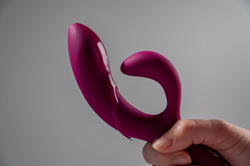 Lube pouring on pink dildo on white background. 