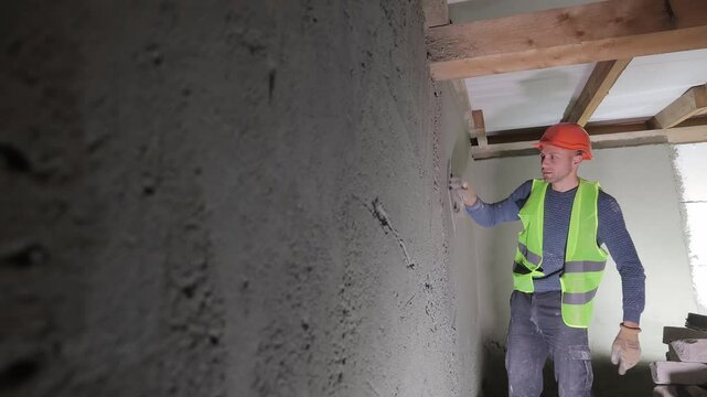 Construction worker plastering wall surface indoors, Worker applying plaster to a wall inside a building
