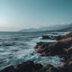 Obraz premium Dramatic coastal scene with rocky shoreline and distant mountains at dusk