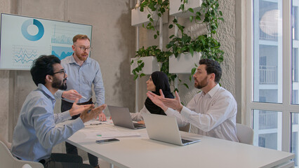 Emotional business team arguing at office discussing financial strategy graphics results diverse...