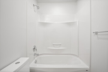 A white bathroom with a white toilet and a white bathtub