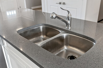 A stainless steel sink with a silver faucet sits on a countertop