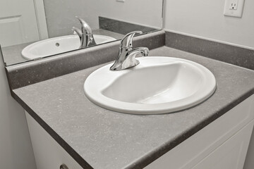 A sink with a silver faucet sits on a grey countertop