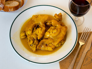 Pig's trotter served on white circular plate with sauce and glass of wine.