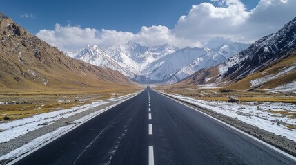 Winding asphalt road stretches into the distance, flanked by towering snow-capped mountains. Lush valleys and dramatic clouds create an awe-inspiring natural backdrop for adventure