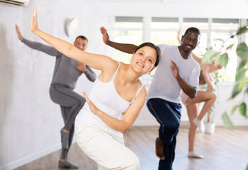 Obraz premium Young woman dancing in multiethnic group in fitness studio