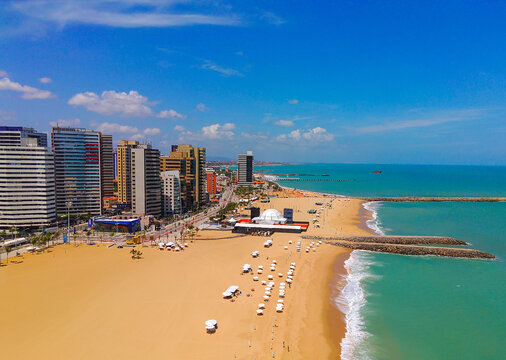 Above view of Iracema beach in Fortaleza, Ceara, Brazil. Golden sand with umbrellas and skyscrapers in the background.