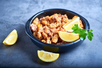 chipirones sobre un fondo de concreto en un plato negro con imagenes cenitales y acompañado de limones todo con colores neutros.