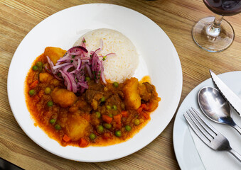 Plate of tasty Peruvian dish - spicy veal served with gravy, rice and onion