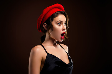 Fototapeta premium Elegant young woman with red beret posing against dark brown background