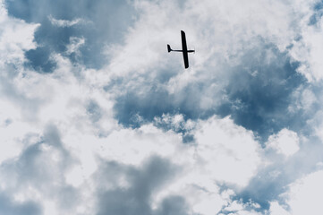 Drone flying high in a blue sky amidst scattered clouds