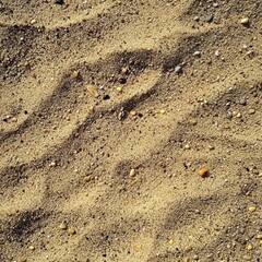 Close-up of beach sand with small pebbles and shadows on a sunny day