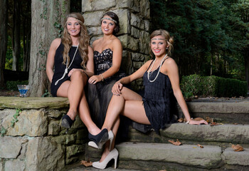 1920's fashion shoot - Three stunning young Caucasian women wearing black vintage appearing dresses...