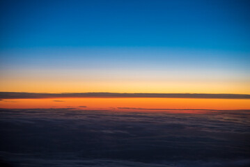 Fototapeta premium Minimalist horizon cloudscape sunrise. Dramatic sky, vibrant blue and orange colors. Aerial view. Just before morning sunrise.