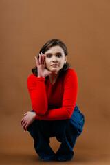 A fashionable young woman in a bold red top and wide-leg denim jeans strikes a dynamic and artistic...