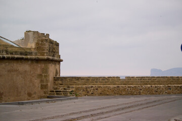 wall of the bastions in Alghero, in the background the outline of the promontory of Capo Caccia...