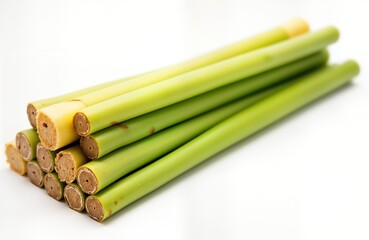 Fototapeta premium Fresh sugarcane stalks stacked on white background. Natural sweetener source for food, beverage concepts. Close-up view of stalks. Illustrates healthy, tropical ingredient. Perfect for food industry.