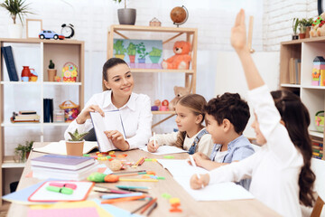 Children study letters in class at school.  They are sitting at the table. They are helped by an adult teacher.