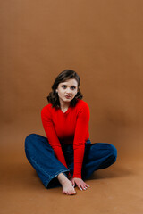 A fashionable young woman in a bold red top and wide-leg denim jeans strikes a dynamic and artistic...