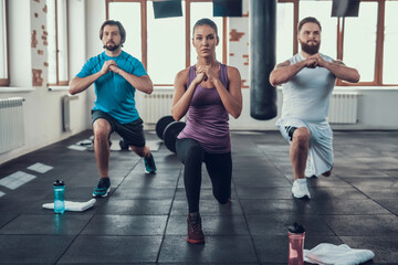 Fototapeta premium Girl And Two Guys Doing Lunge Exercises In Gym. Training Day. Fitness Club. Healthy Lifestyle. Powerful Athlete. Active Holidays. Crossfit Concept. Comfortable Sportswear. Legs Stretching.