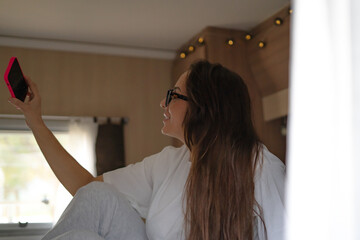young woman laughing while looking at her phone in a camper van
