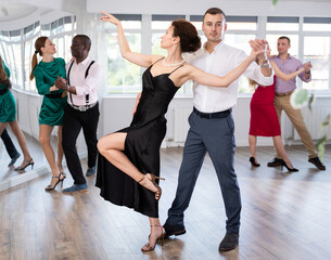 Fototapeta premium Happy woman enjoying passionate Latin American dancing with male partner in dance hall