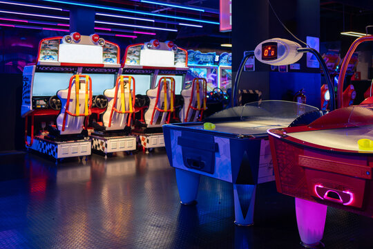 Game Center: Gaming chairs and table in illuminated arcade game zone. Children's play area in shopping center 