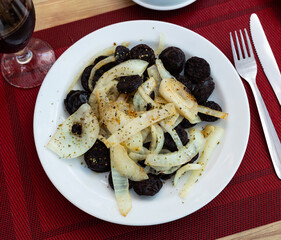 Morcilla con cebolla - fried blood sausage with onion on table. Spanish cuisine