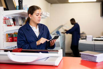 Technical worker of printing house calculates cost of payment for work on the calculator