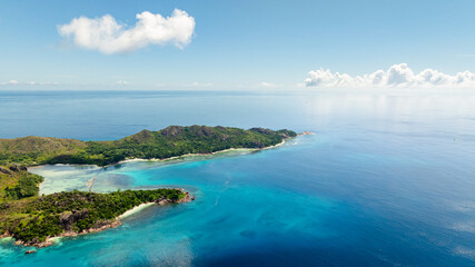 Peaceful island stretches into the expansive turquoise sea, with gentle waves and a serene horizon. Curieuse, Seychelles.