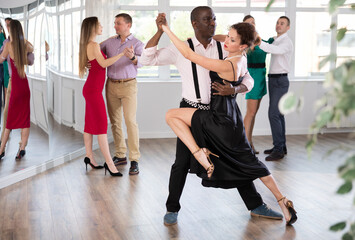 Pair of woman and African American man enjoying of sensual tango dance in choreo class. Exciting...