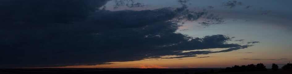 Landscape at sunset. Tragic gloomy sky. Panorama. Crimson twilight. Heavy, gloomy, dark clouds.