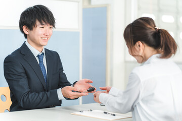 受付で車の鍵の受け渡しをする男性スタッフと顧客の女性
