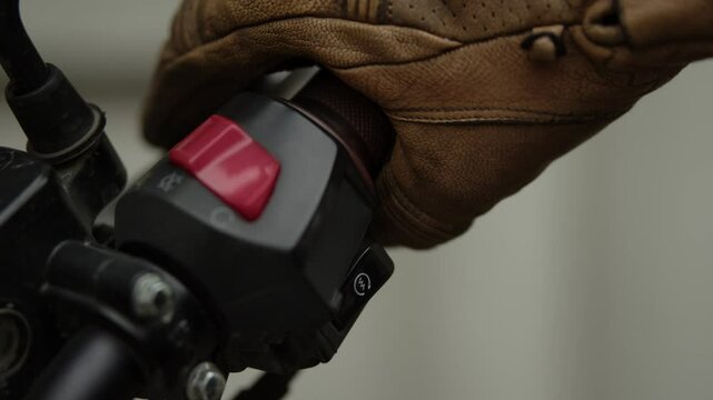 The biker takes the steering wheel of the motorcycle with his right hand, presses the kill switch and presses the starter button to start the motorcycle, turns the gas handle