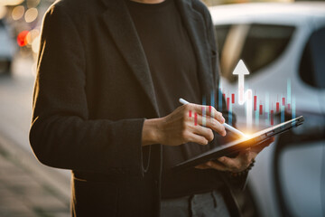 A businessman using a tablet with financial and stock market data visualizations overlayed