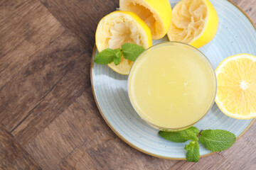 Glass of lemon juice and fresh fruits on wooden table, top view. Space for text
