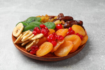 Mix of different dried fruits in bowl on light grey table, closeup