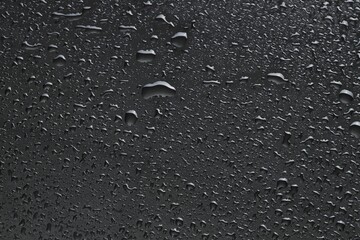 Water drops on dark grey glass surface, top view