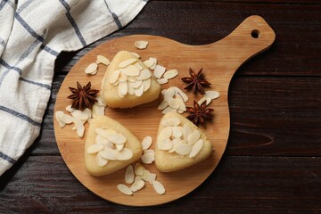 Pieces of delicious sweet semolina halva with almond flakes and spices on wooden table, top view
