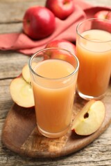 Tasty apple juice in glasses and fresh fruits on wooden table, closeup