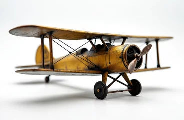 Vintage model biplane stands on white surface. Weathered gold finish gives plane antique look. Design detailed with visible propeller, metal chassis. Decorative piece evokes sense of nostalgic travel