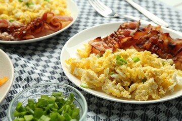 Tasty brunch. Delicious scrambled eggs and bacon served on table, closeup