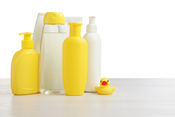 Baby cosmetic products and bath duck on wooden table against white background