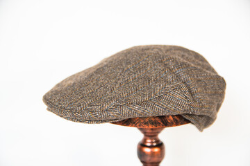 Concept photo of a scally cap or flat cap made of khaki herringbone tweed fabric mounted on a...