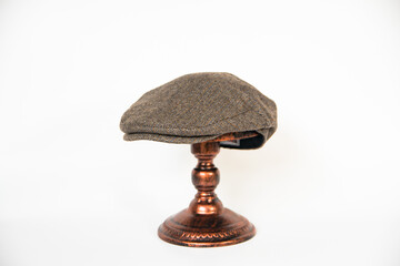 Concept photo of a scally cap or flat cap made of khaki herringbone tweed fabric mounted on a...