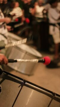 detail of a person playing bass drum instrument with drumsticks