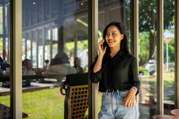 A woman is talking on her cell phone while standing in front of a window