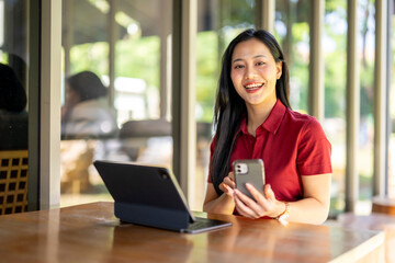 Fototapeta premium A woman is sitting at a table with a laptop and a cell phone