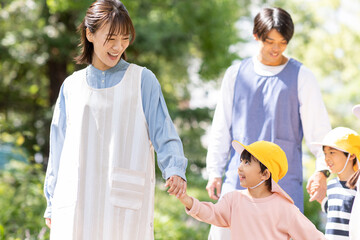 公園を散歩する保育士と園児