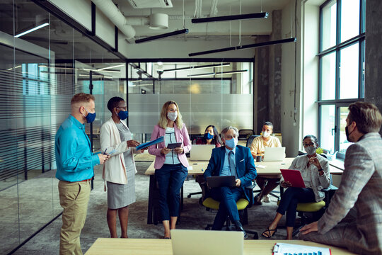 Business meeting with professionals wearing face masks in modern office - Powered by Adobe